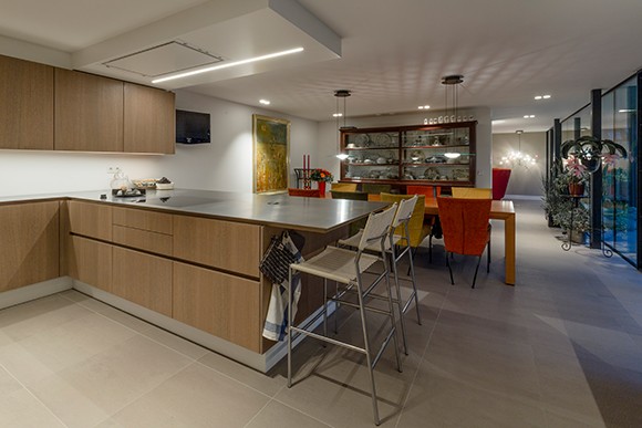 Licht eiken keuken met een rvs werkblad en witte moderne barkrukken